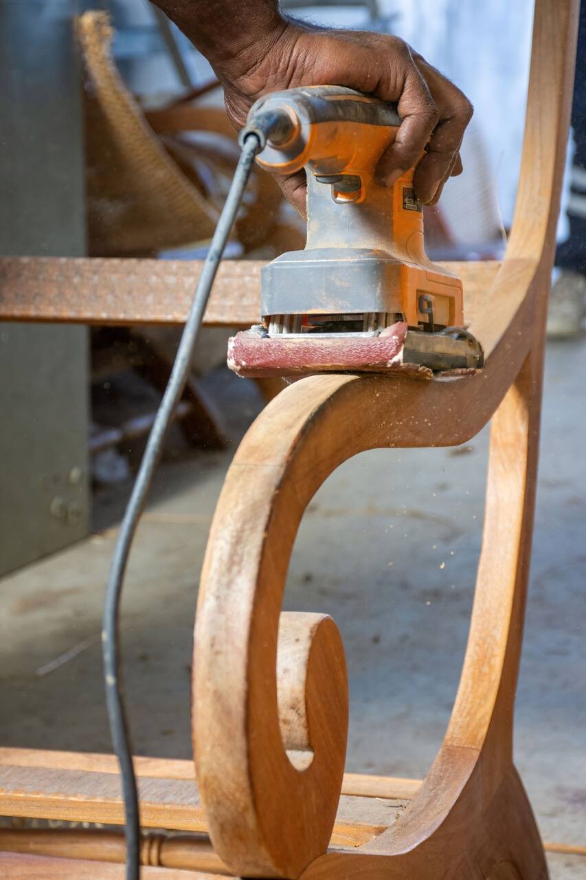 Ponçage de l'accoudoir en volute d'un fauteuil à l'atelier