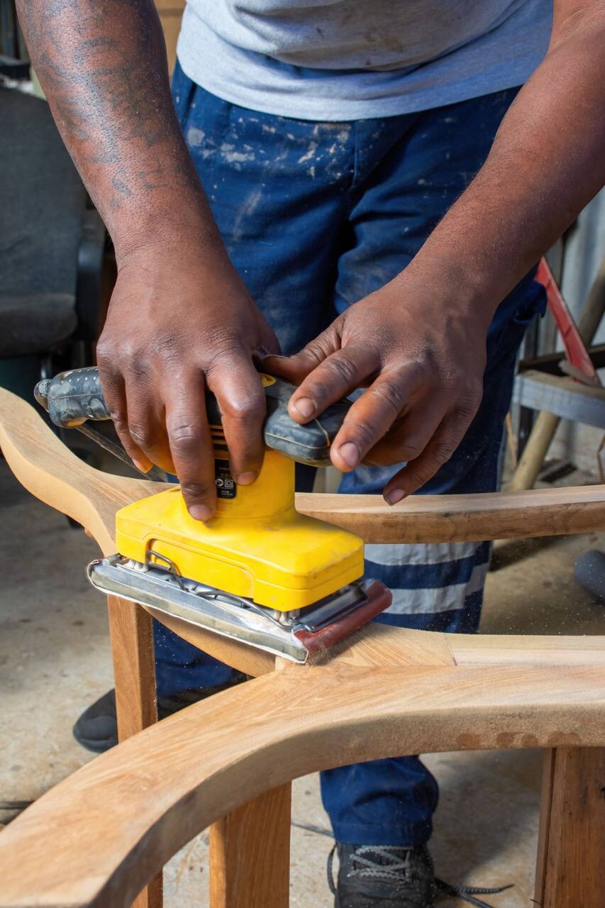 Mains ponçant l'accoudoir d'un fauteuil en bois