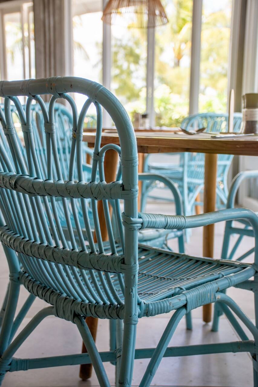 Chaise en rotin turquoise dans un restaurant ouvert sur le jardin